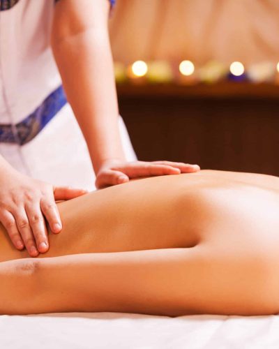 Massaging stress away. Close-up of young shirtless woman lying on front while massage therapist massaging her back